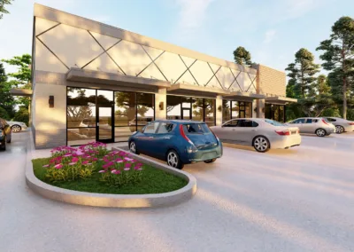 Cars parked outside a modern building with large windows and a flower bed in the foreground at sunset.